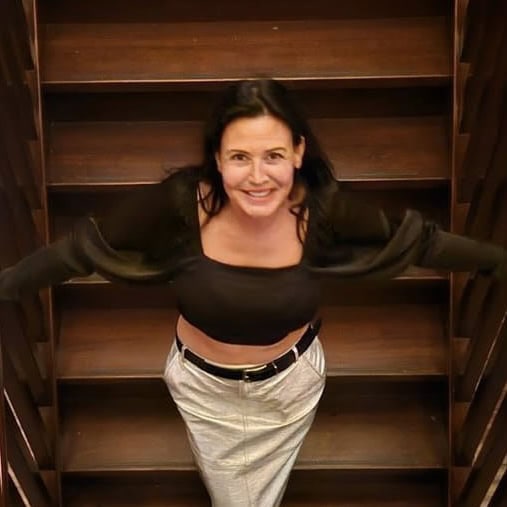 Vrouw die op een trap staat met open armen, straalt rust en kracht uit.