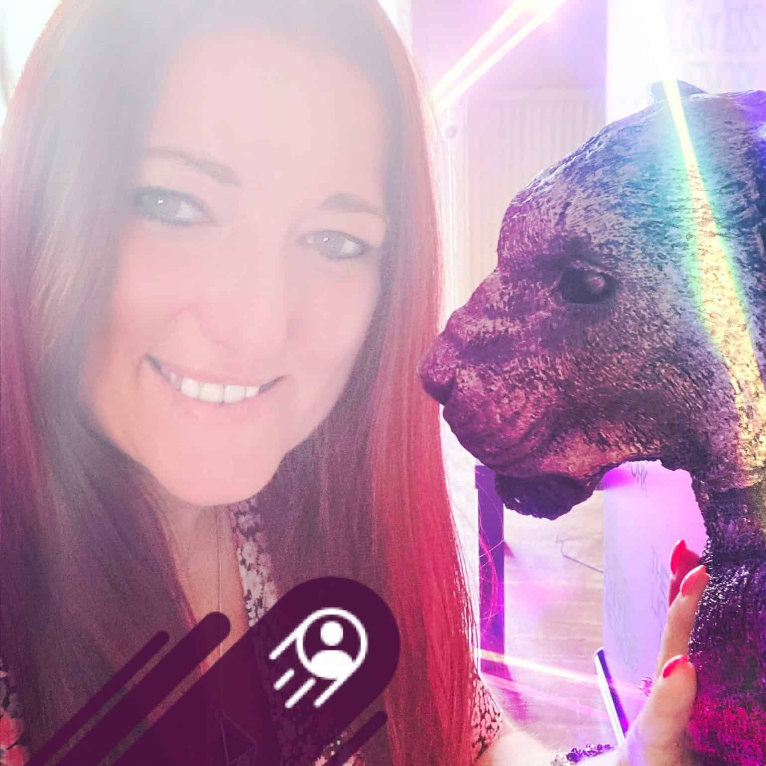 Vrouw met glimlach naast een kunstwerk van een leeuw, symboliseert kracht en spiritualiteit.