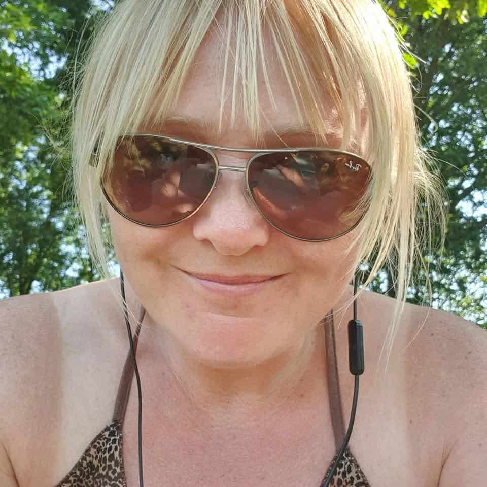 Vrouw mediteert buiten in de natuur met zonneschijn en groene bomen.